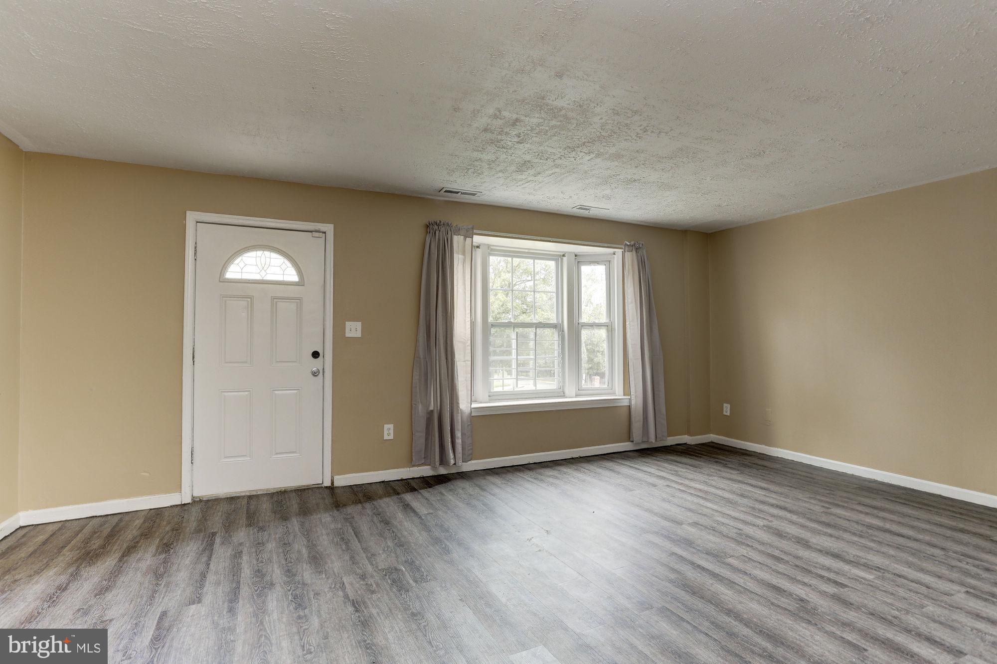 1925 Addison Road South District Heights, MD 20747 - Photo 2 of 9 an empty room with wooden floor and windows