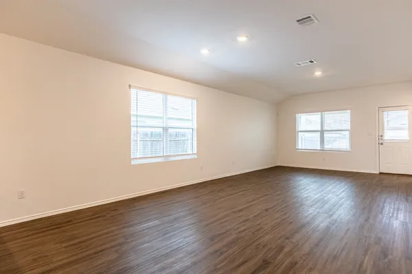 an empty room with wooden floor and windows
