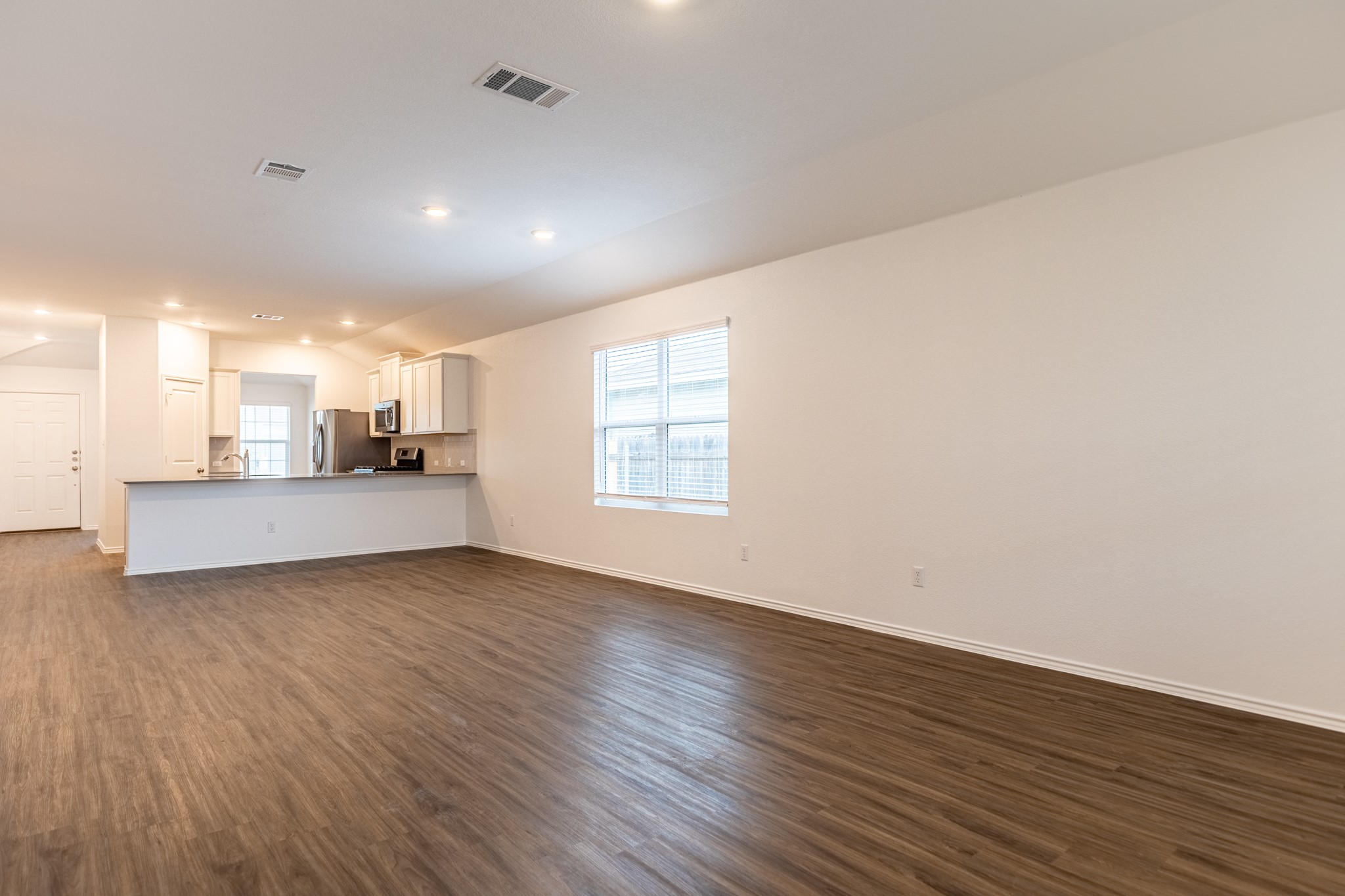 175 Silver Springs Bend Kyle, TX 78640 - Photo 16 of 33 Unfurnished living room featuring dark wood-style floors, recessed lighting, and vaulted ceiling