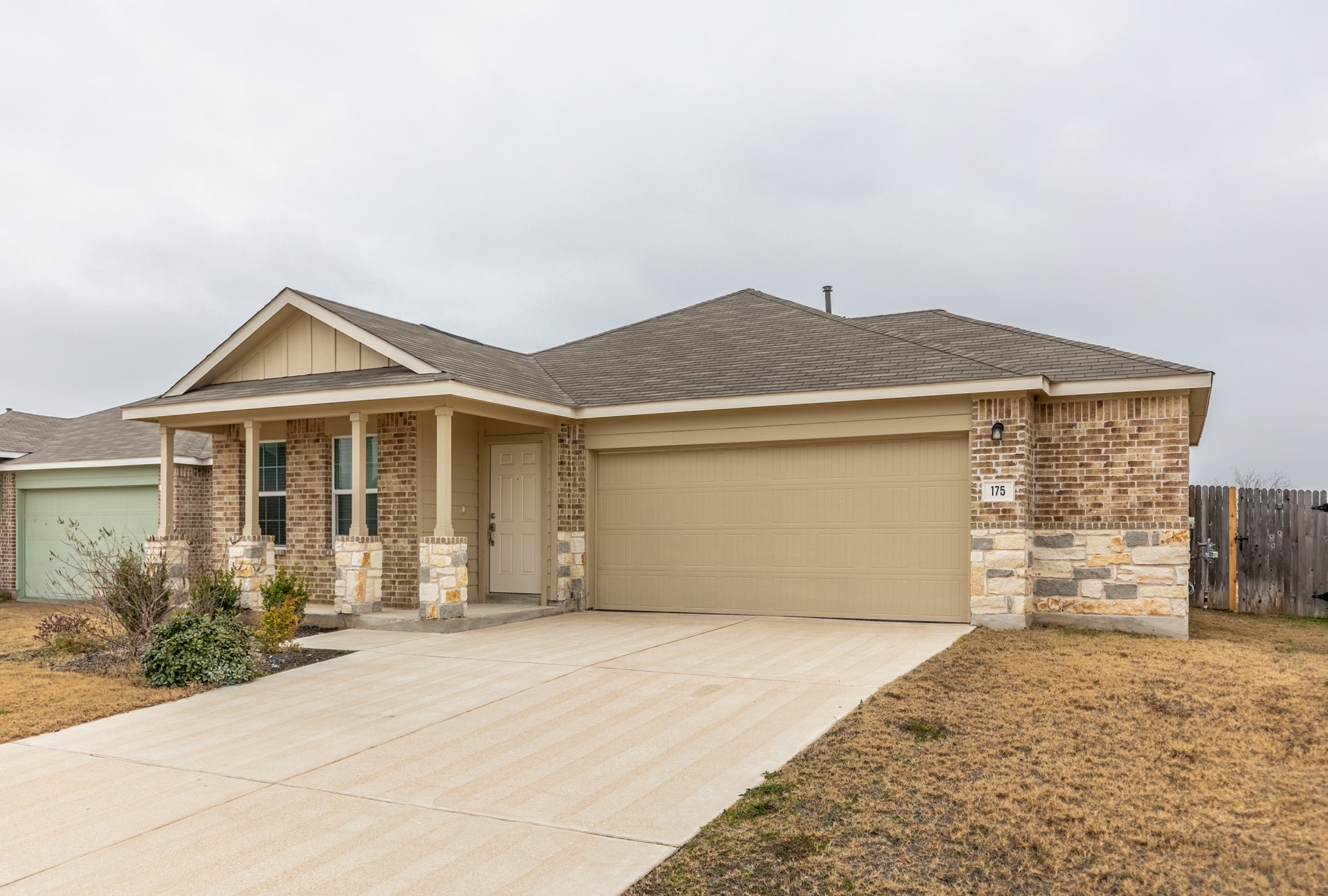 175 Silver Springs Bend Kyle, TX 78640 - Photo 2 of 33 View of front of home featuring stone siding, an attached garage, concrete driveway, and roof with shingles