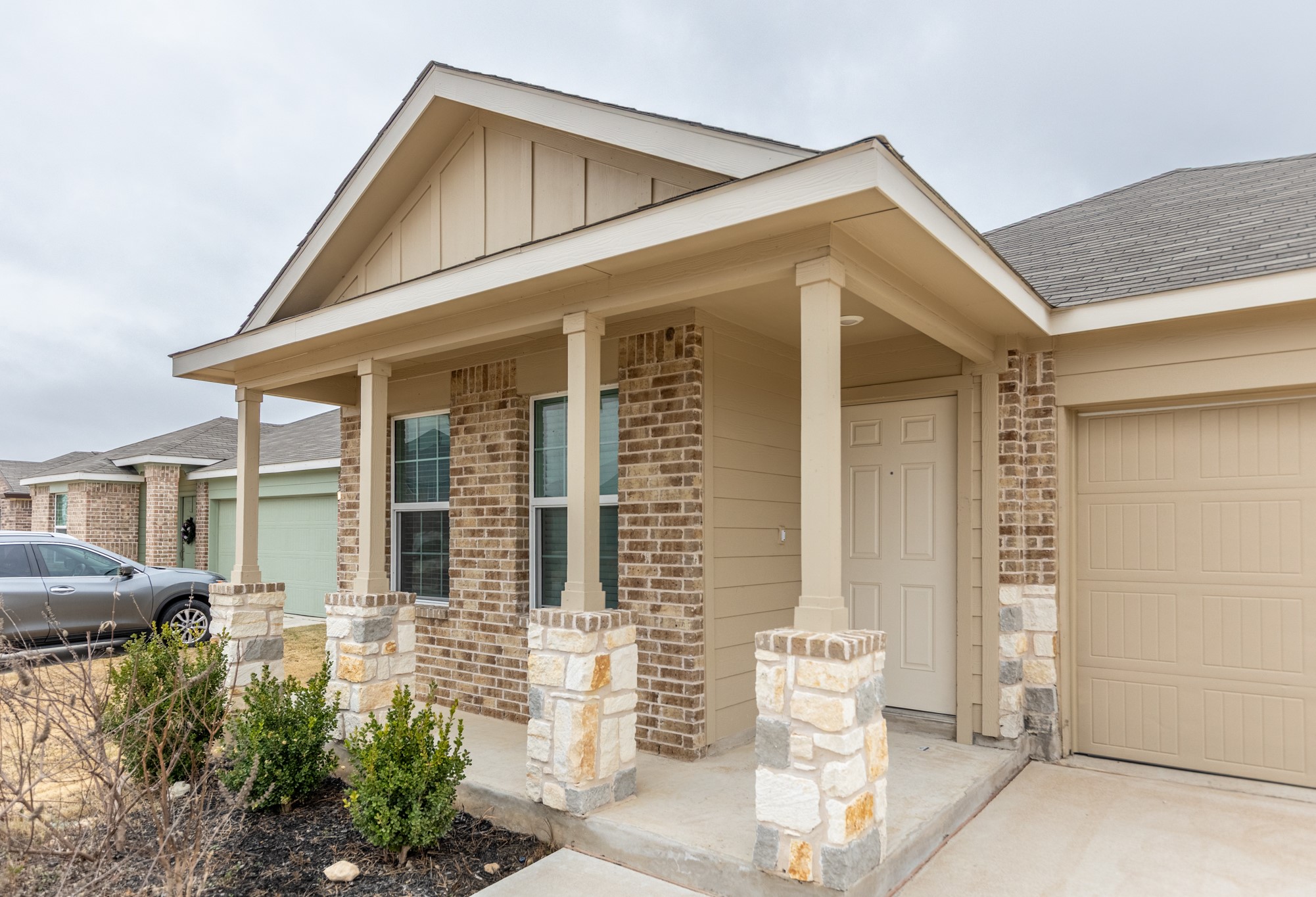 175 Silver Springs Bend Kyle, TX 78640 - Photo 3 of 33 Entrance to property with brick siding, covered porch, an attached garage, board and batten siding, and roof with shingles