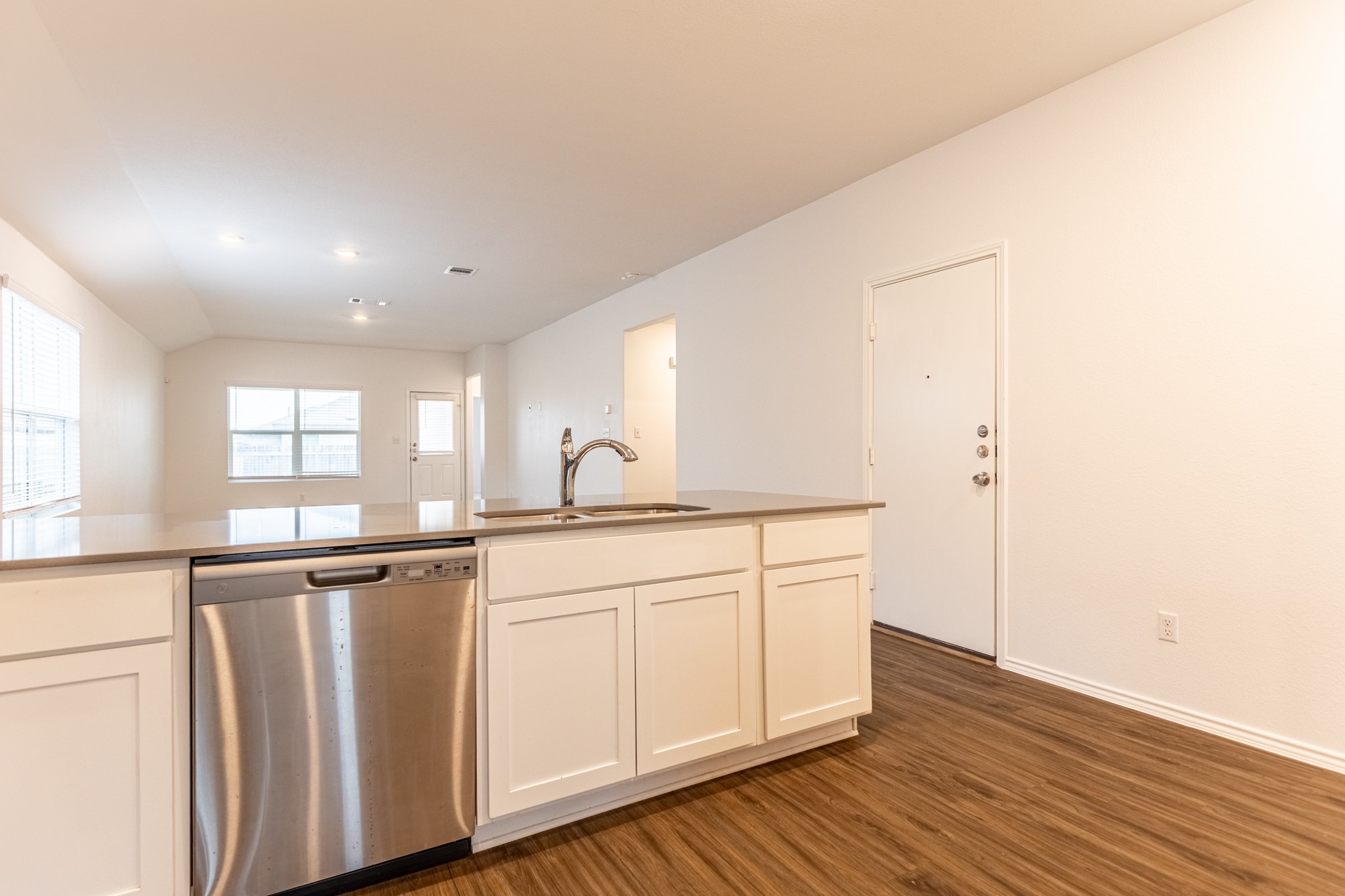 175 Silver Springs Bend Kyle, TX 78640 - Photo 10 of 33 Kitchen featuring dishwasher, white cabinets, dark wood-style flooring, and lofted ceiling