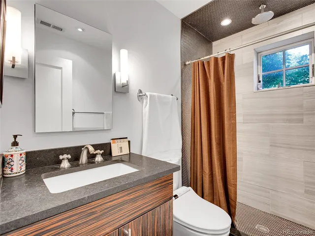 a bathroom with a granite countertop sink toilet and shower