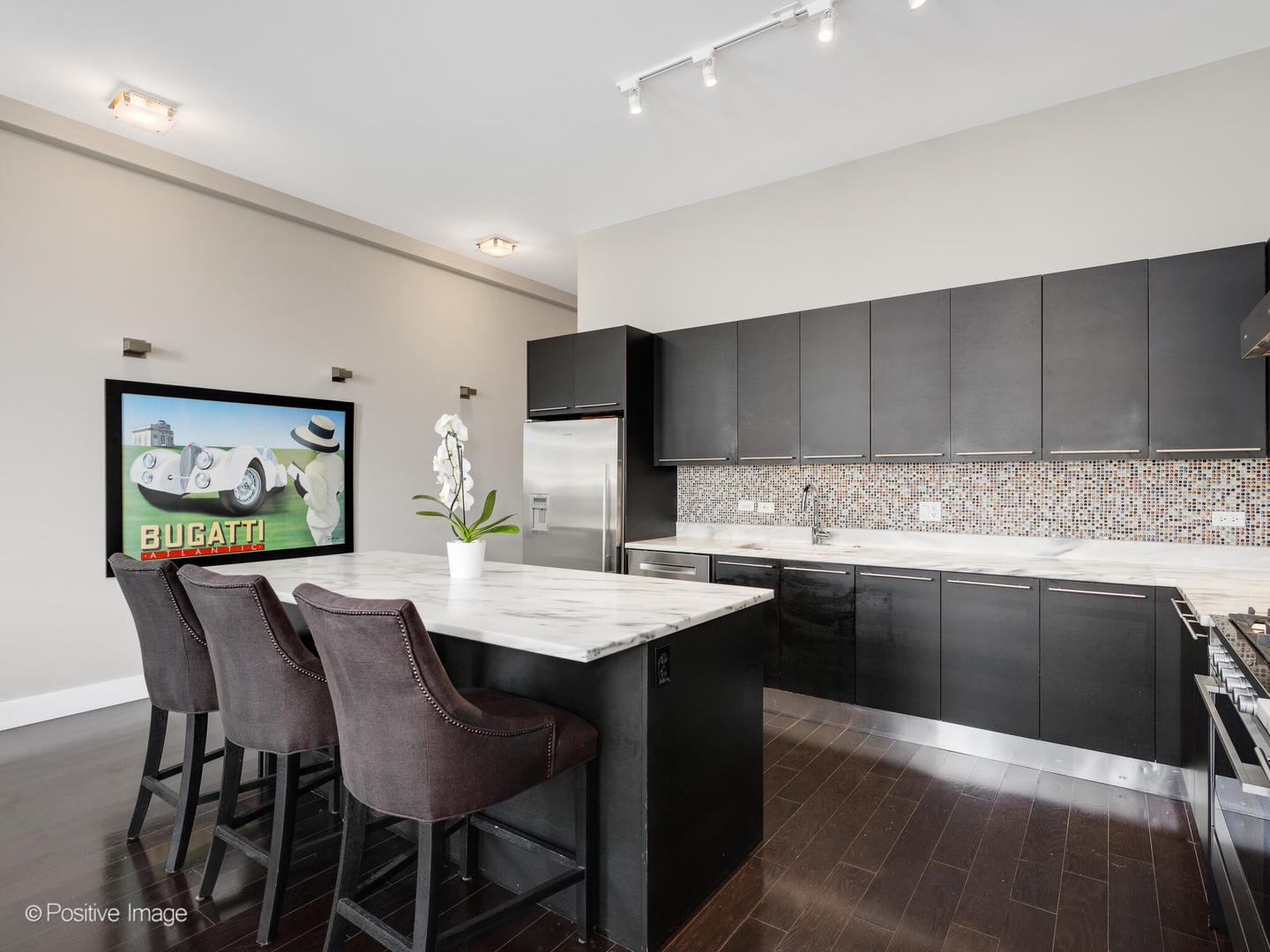 23 North Aberdeen Street, Unit 4S Chicago, IL 60607 - Photo 12 of 24 a kitchen with stainless steel appliances kitchen island granite countertop a table chairs and a refrigerator