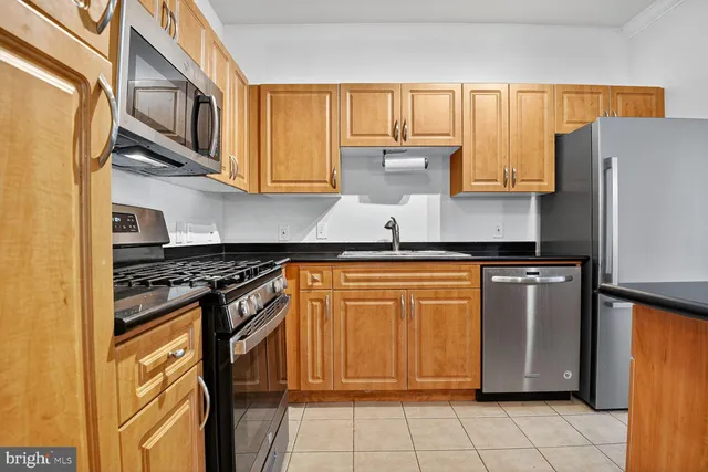 a kitchen with stainless steel appliances granite countertop a stove top oven a refrigerator and white cabinets