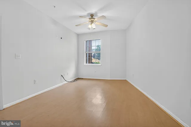 an empty room with a chandelier fan and windows