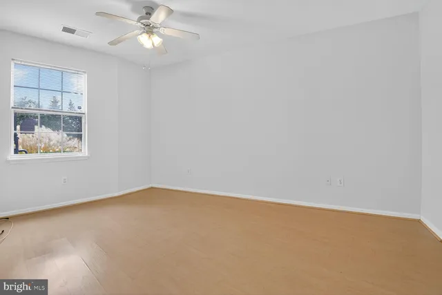 an empty room with a window and a fan