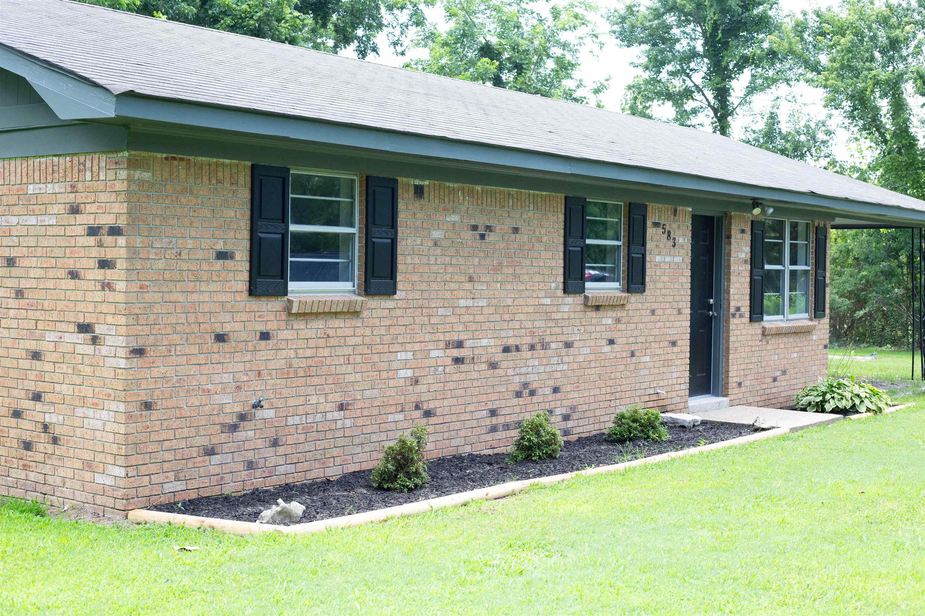 583 Armstrong Road Drummonds, TN 38023 - Photo 2 of 14 Brick exterior with dark shutters, a dark front door, and a covered entry