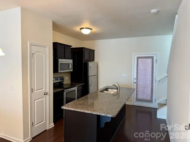 a kitchen with stainless steel appliances granite countertop a refrigerator and a stove top oven