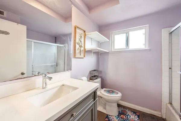 a bathroom with a granite countertop sink toilet a large mirror and a window