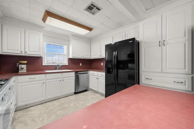 a kitchen with granite countertop a refrigerator and cabinets