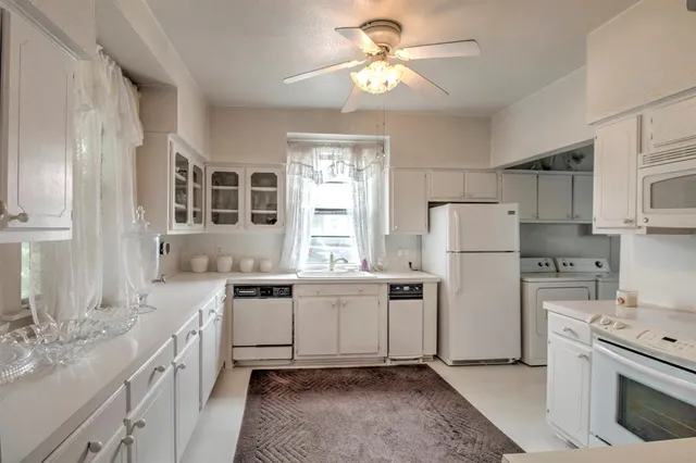 a kitchen with a refrigerator a sink and dishwasher with white cabinets