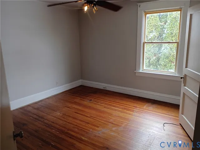 an empty room with wooden floor cabinet and windows
