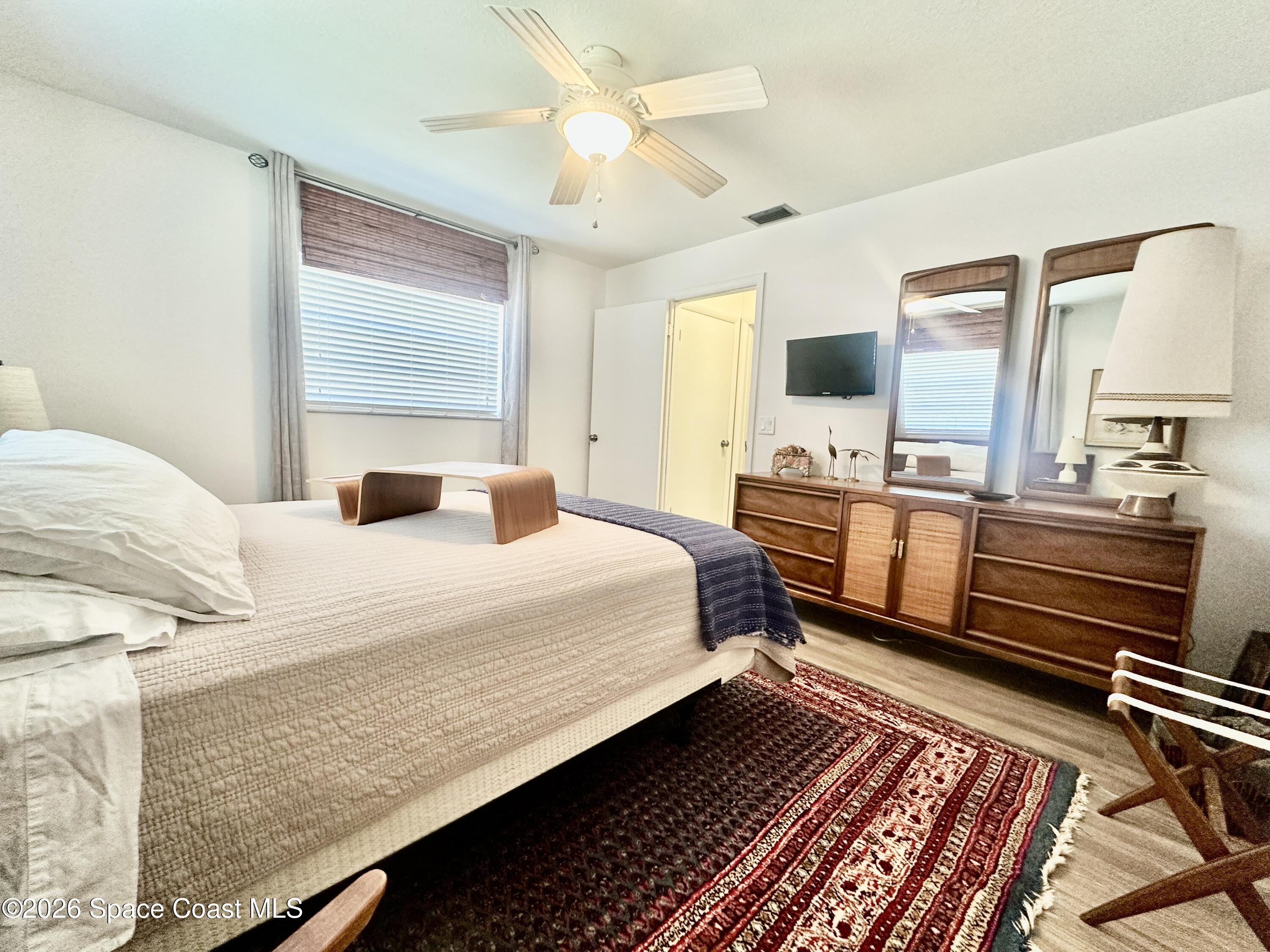 410 Surf Road Melbourne Beach, FL 32951 - Photo 16 of 29 a bedroom with a bed wooden floor and a table