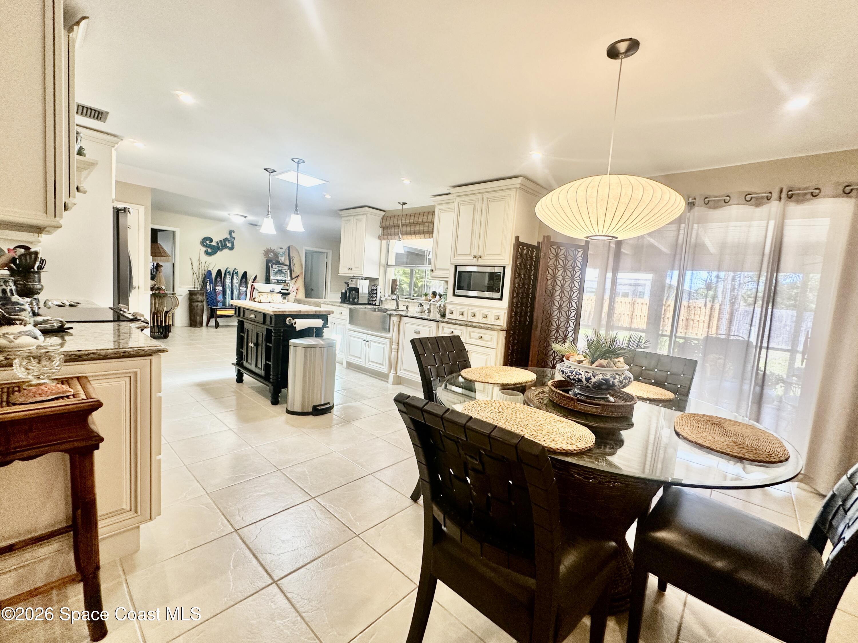 410 Surf Road Melbourne Beach, FL 32951 - Photo 7 of 29 a kitchen with stainless steel appliances kitchen island granite countertop a table chairs and a sink