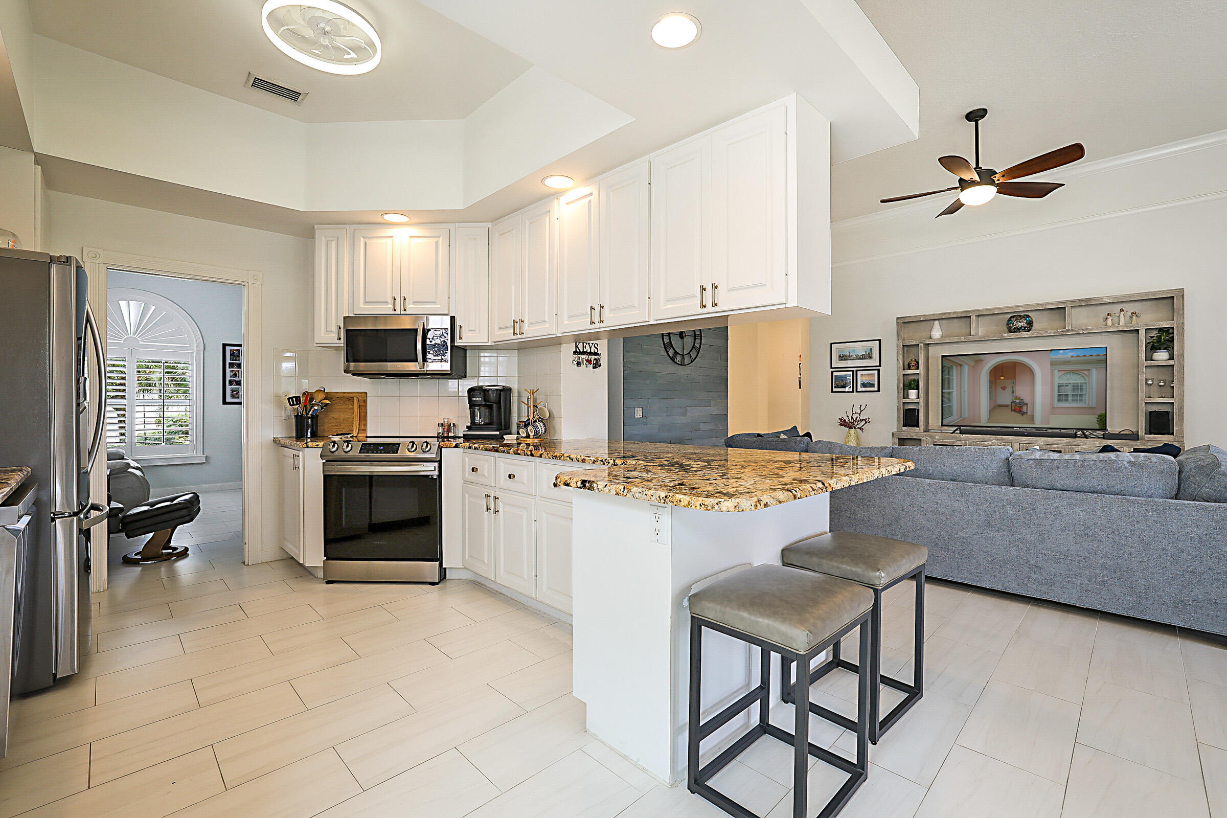 9520 Southwest Wedgewood Lane Stuart, FL 34997 - Photo 12 of 53 a kitchen with stainless steel appliances granite countertop a stove top oven a sink dishwasher a refrigerator and white cabinets with wooden floor