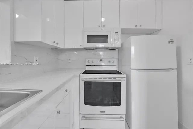 a kitchen with stainless steel appliances a stove a microwave and white cabinets