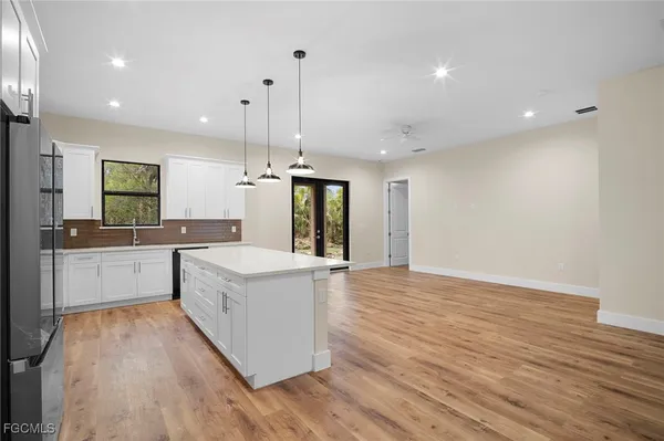 a large white kitchen with wooden floors and stainless steel appliances