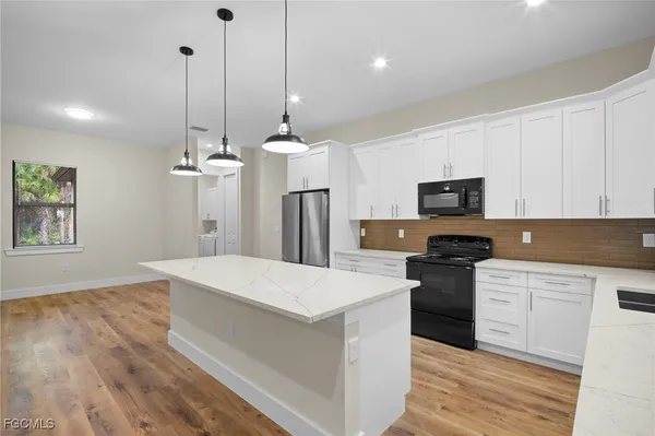 a kitchen with stainless steel appliances kitchen island granite countertop a refrigerator a stove a microwave oven a sink with island and chairs