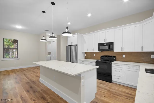 a kitchen with stainless steel appliances kitchen island granite countertop a refrigerator a stove a microwave oven a sink with island and chairs