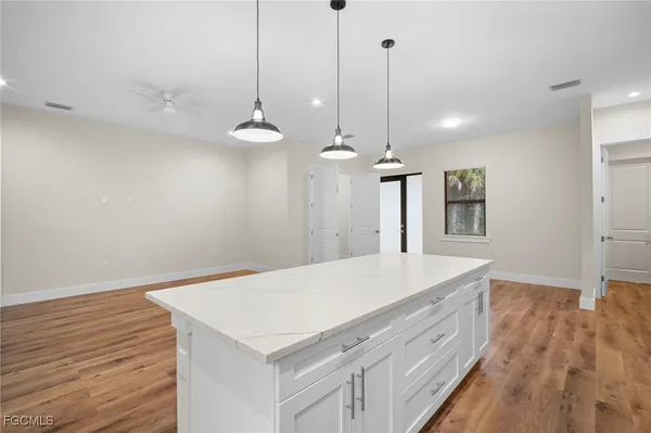 a room with a chandelier chandelier fan and wooden floor