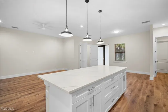 a room with a chandelier chandelier fan and wooden floor