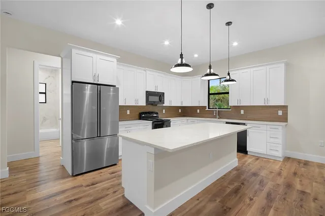 a large kitchen with stainless steel appliances a refrigerator a stove a sink and a wooden floor