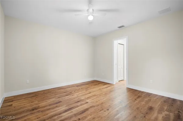 an empty room with wooden floor and fan