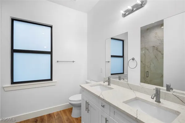 a bathroom with a toilet a sink a mirror and vanity