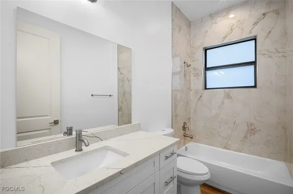 a bathroom with a granite countertop sink a toilet and shower