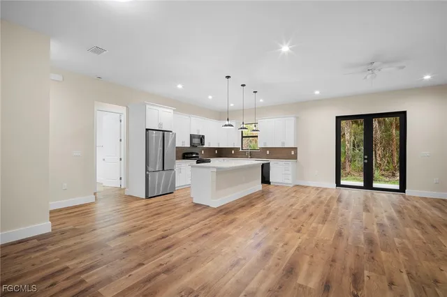 a large kitchen with stainless steel appliances kitchen island a large counter top and a refrigerator