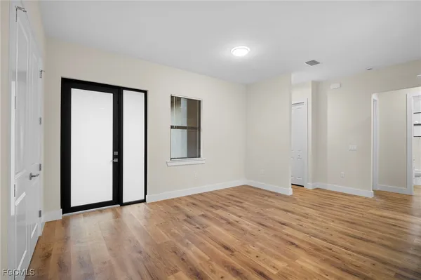 a view of empty room with wooden floor and fan