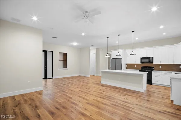 a large white kitchen with kitchen island a sink appliances and a couch
