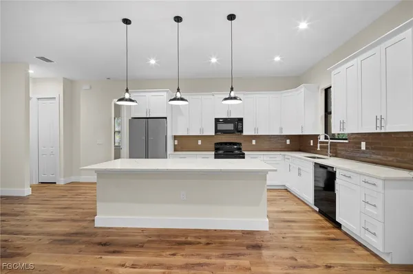 a large white kitchen with stainless steel appliances