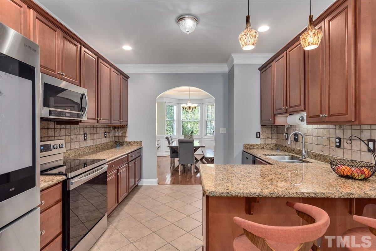 6 Piccadilly Court Durham, NC 27713 - Photo 7 of 27 a kitchen with stainless steel appliances granite countertop a stove a sink a microwave and wooden cabinets