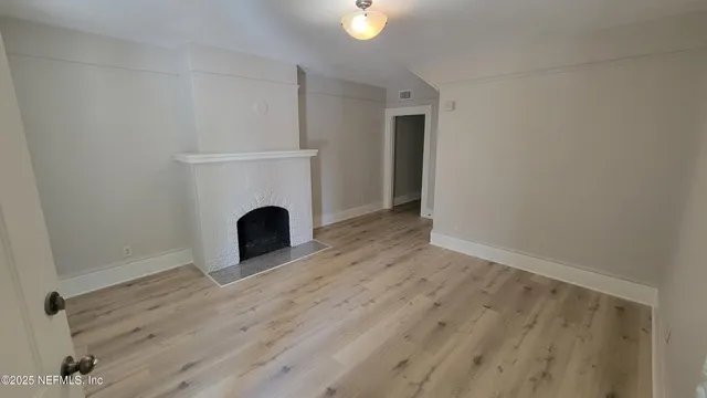 a view of an empty room with a fireplace and a window