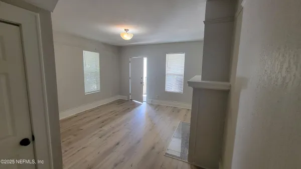 a view of an empty room with wooden floor and a window