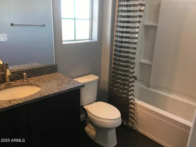a bathroom with a granite countertop toilet sink and mirror