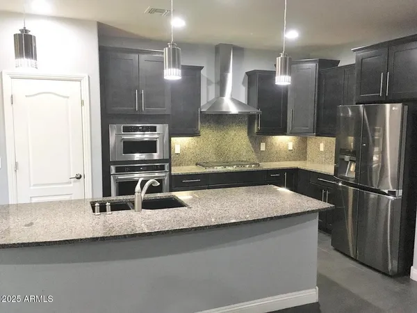 a kitchen with kitchen island a counter top space a sink and stainless steel appliances