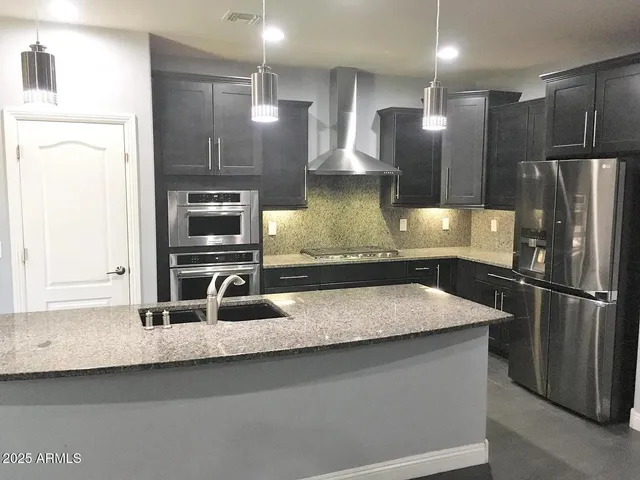 a kitchen with kitchen island a counter top space a sink and stainless steel appliances