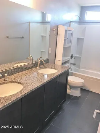 a bathroom with a granite countertop sink a toilet a mirror and bathtub