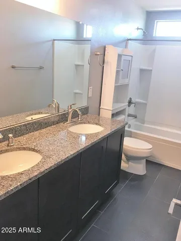 a bathroom with a granite countertop sink a toilet a mirror and bathtub