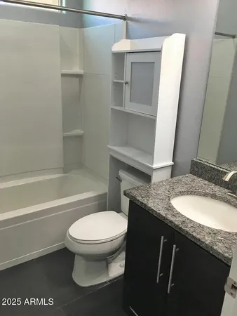 a bathroom with a granite countertop toilet sink and mirror