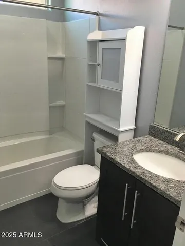 a bathroom with a granite countertop toilet sink and mirror