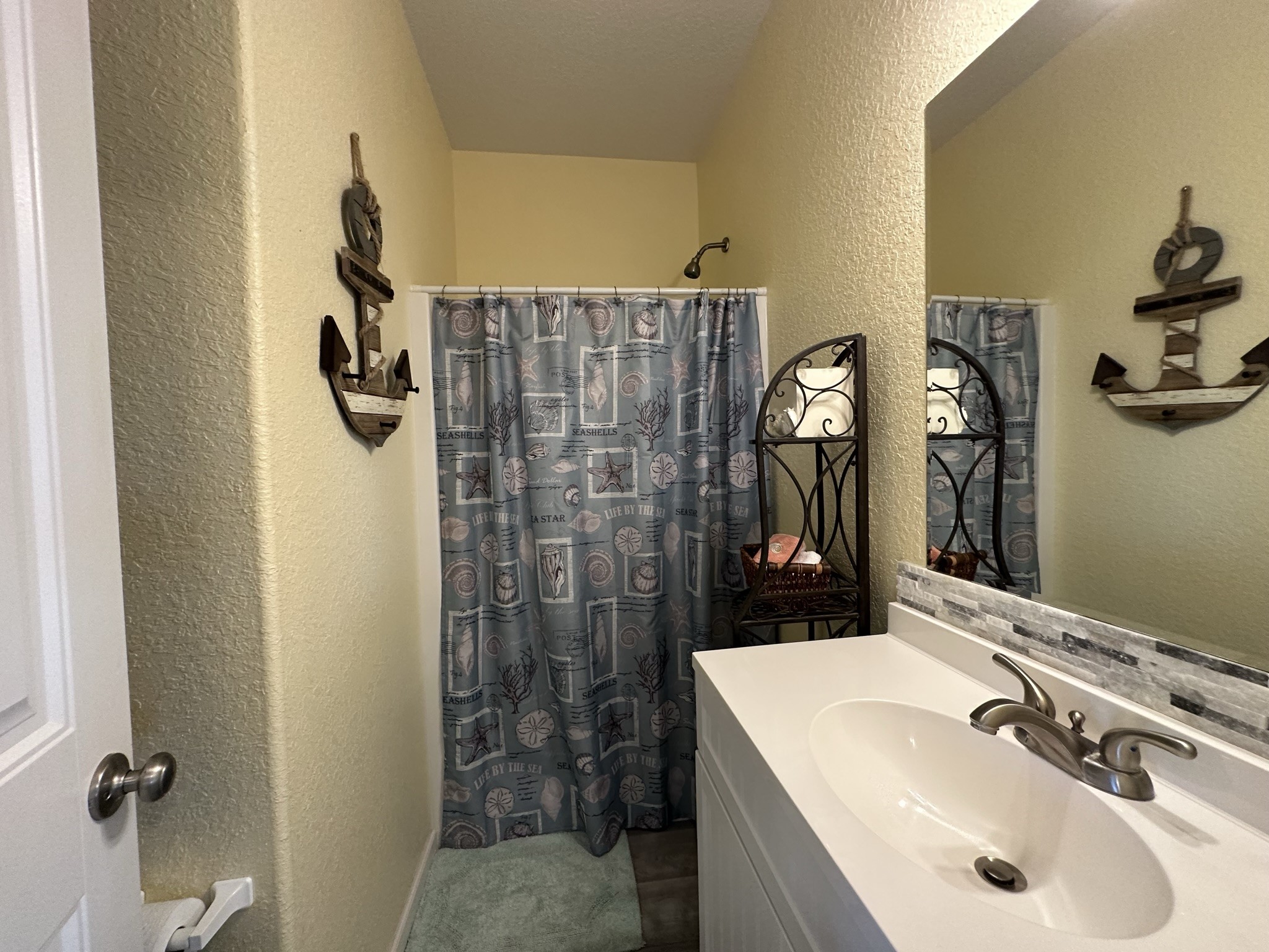 124 Howard Avenue, Unit D Surfside Beach, TX 77541 - Photo 28 of 50 a bathroom with a sink mirror and shower