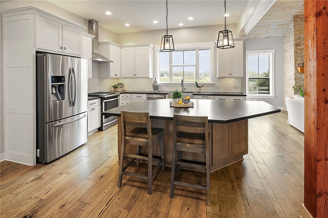 7323 River Ridge Drive College Station, TX 77845 - Photo 15 of 39 a kitchen with stainless steel appliances kitchen island granite countertop a table chairs refrigerator and wooden cabinets