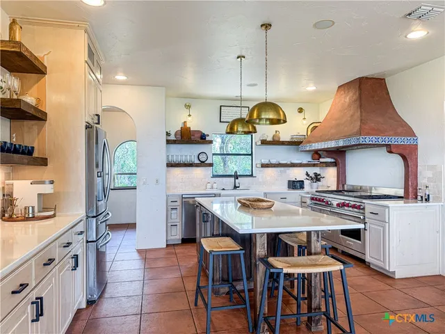 a kitchen with kitchen island granite countertop a sink a stove and a wooden floors