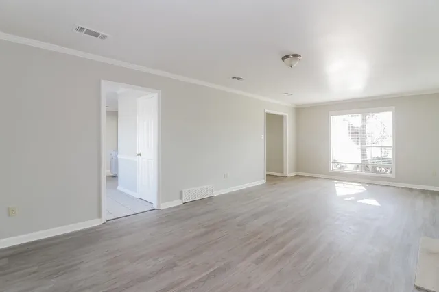 a view of an empty room with wooden floor and window