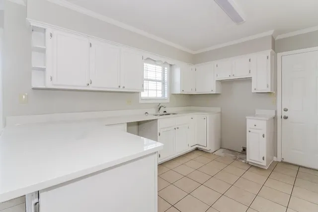 a kitchen with white cabinets appliances and a window