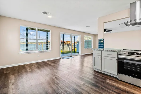 a view of an empty room with a window and wooden floor